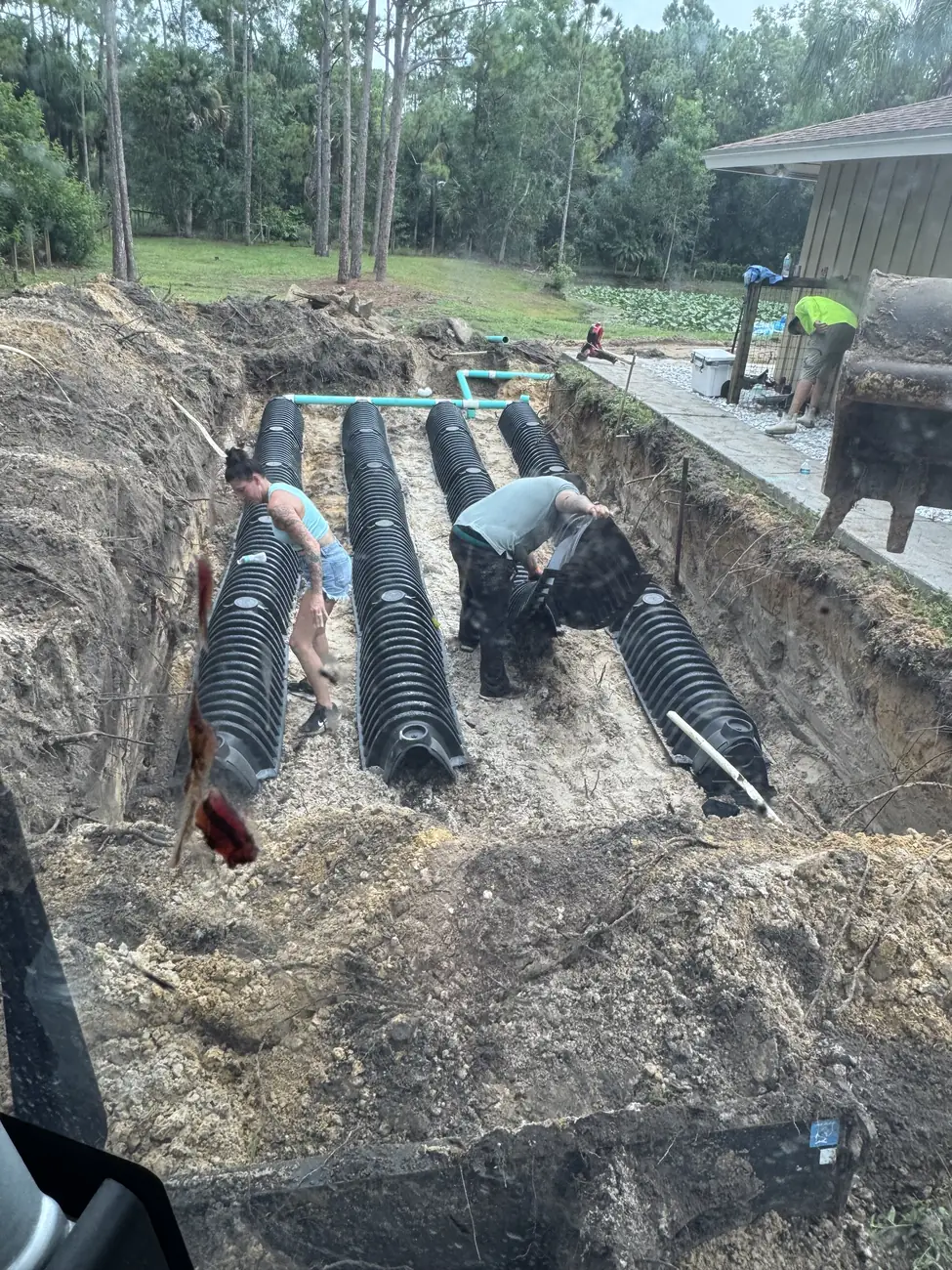 Crew setting chambers in a drain field trench